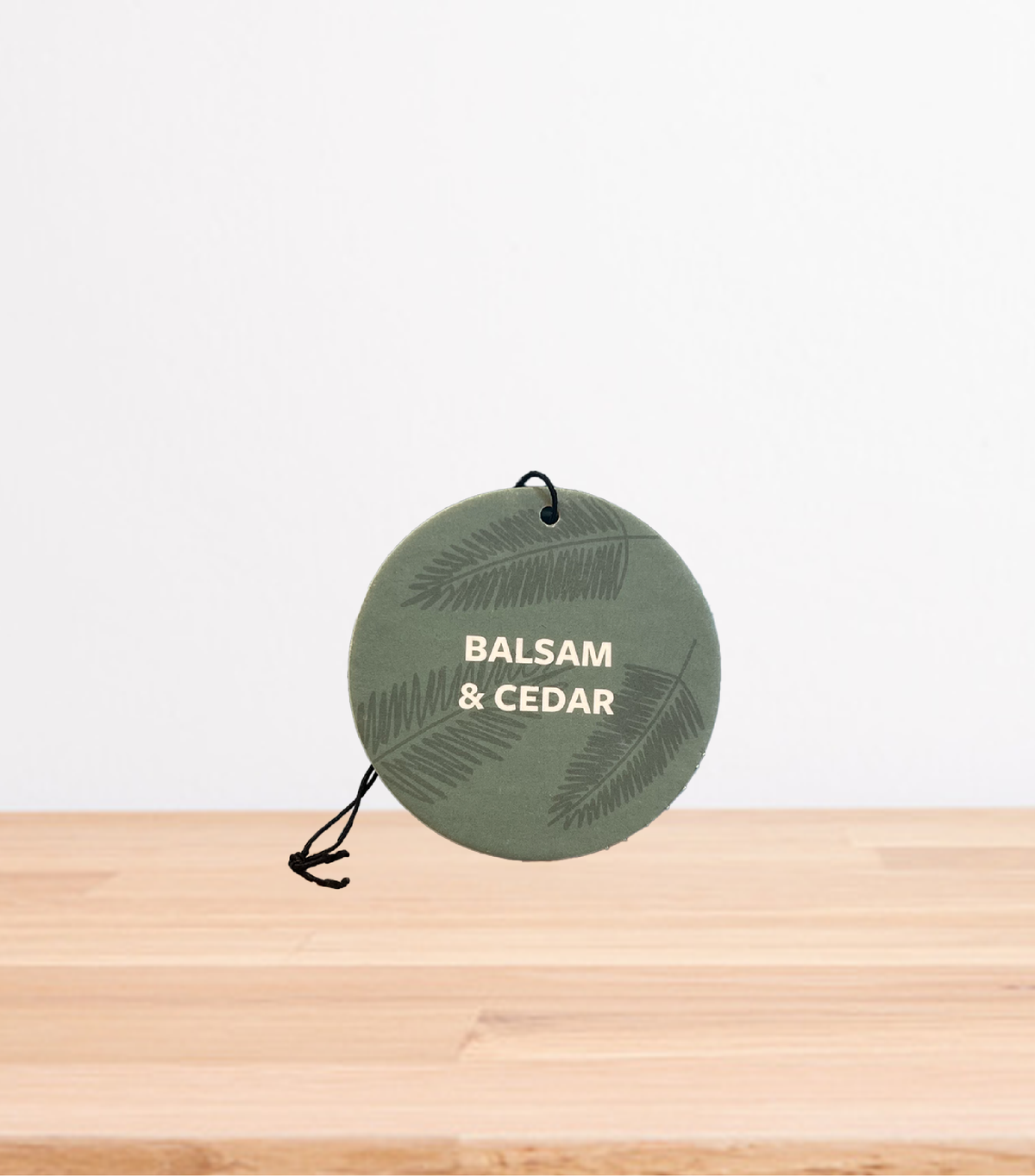 A Balsam & Cedar Car Freshener on a wooden table.