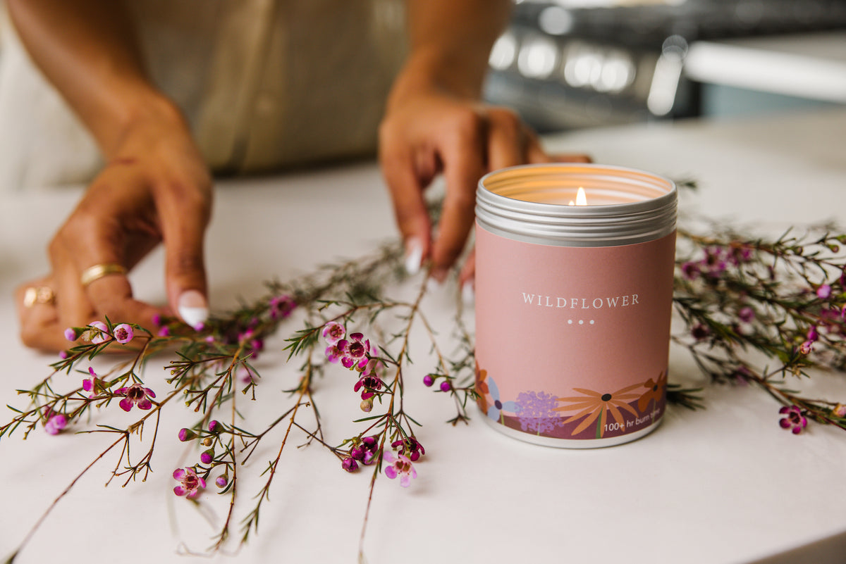 Woman weaving bouquet of flowers surrounding a candle.
