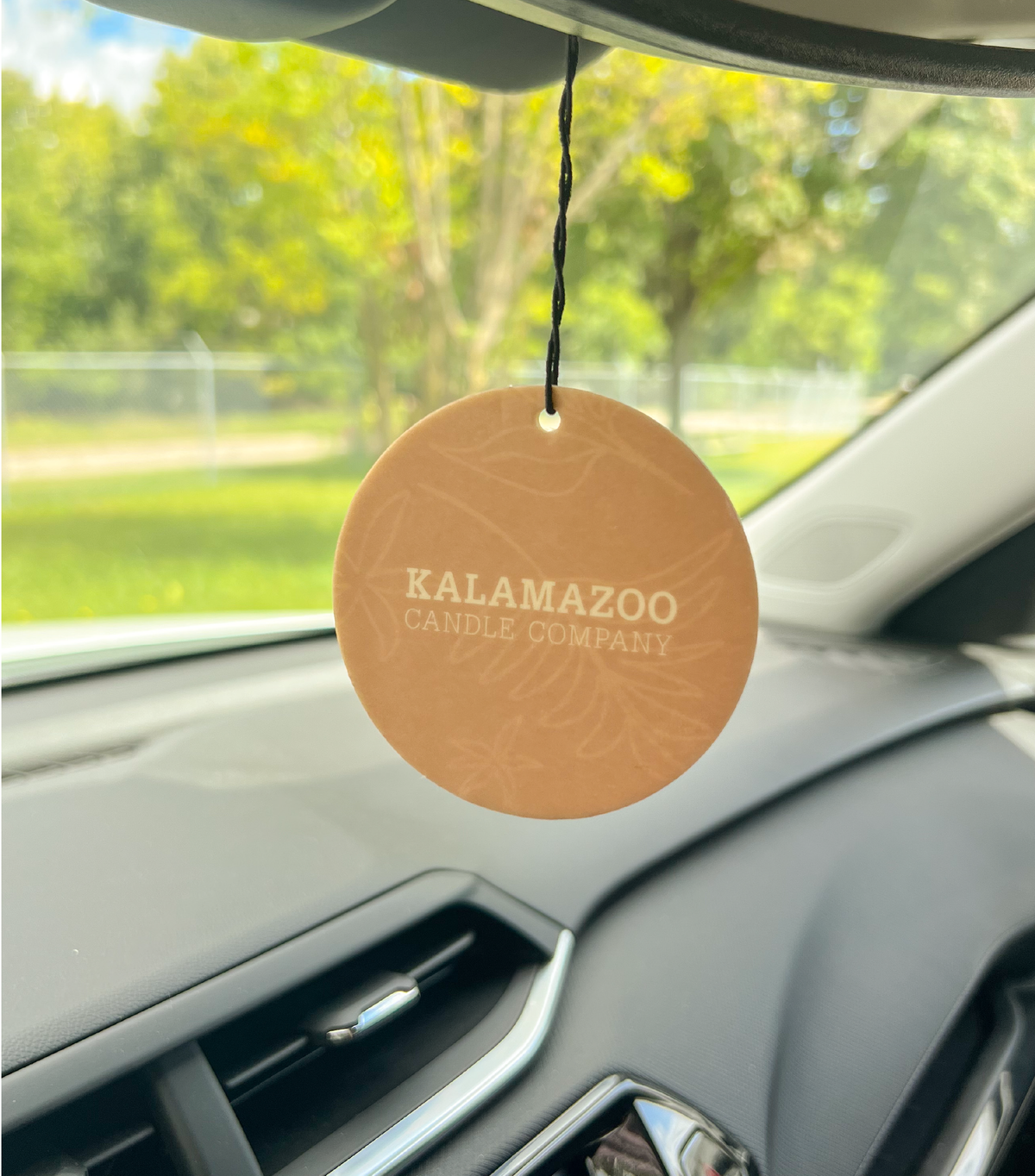 The back of a white tea & ginger car freshener hanging in a car.