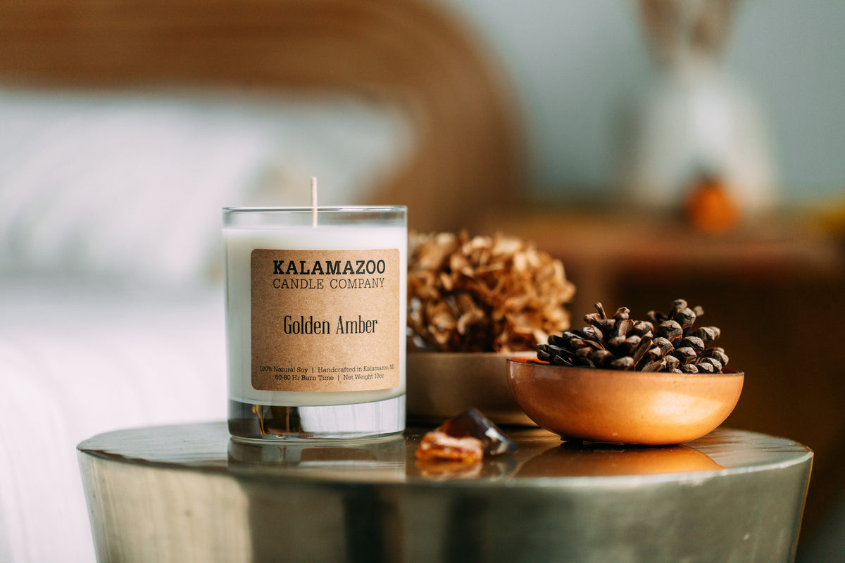 A Golden Amber Candle next to pinecones
