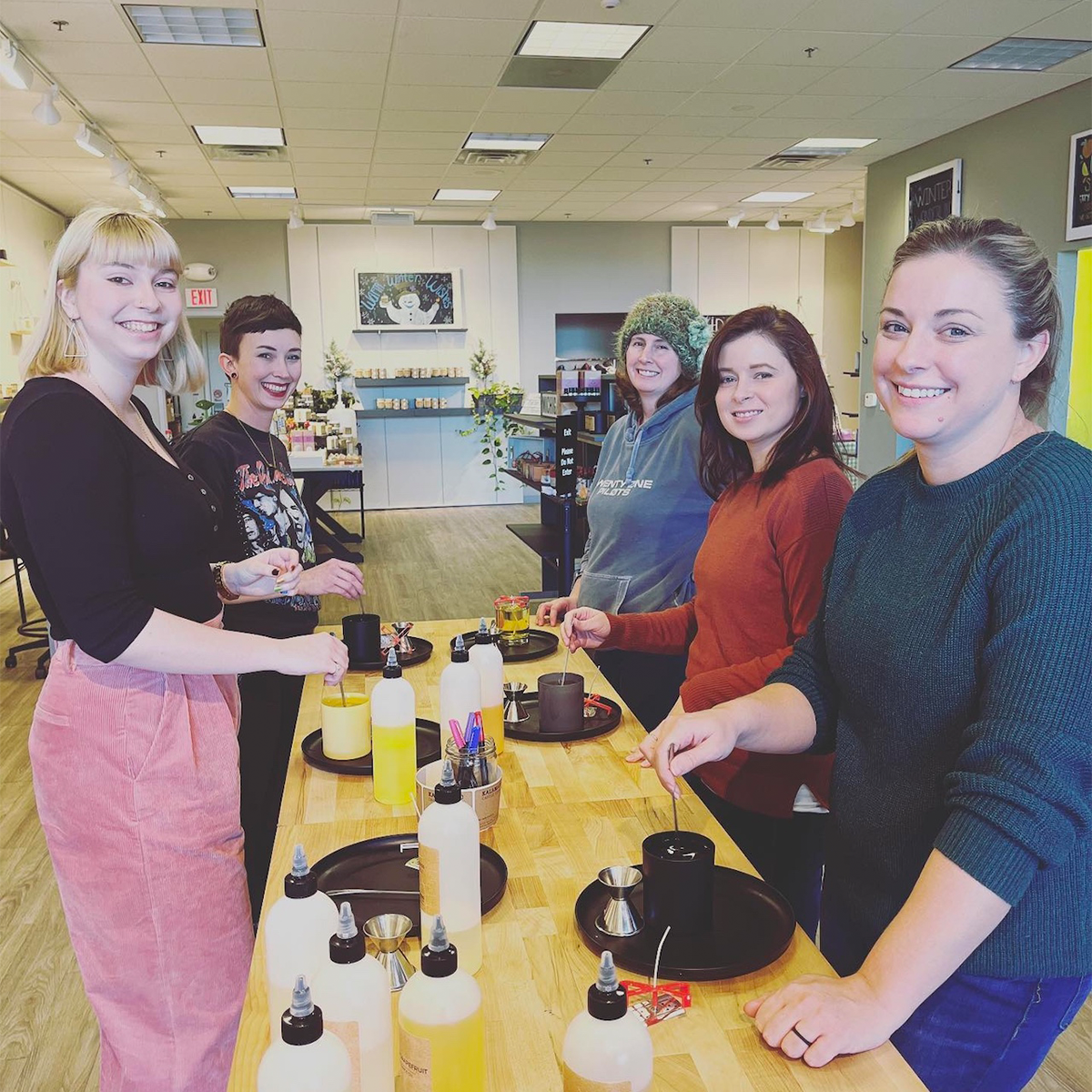 5 people making candles on wooden table